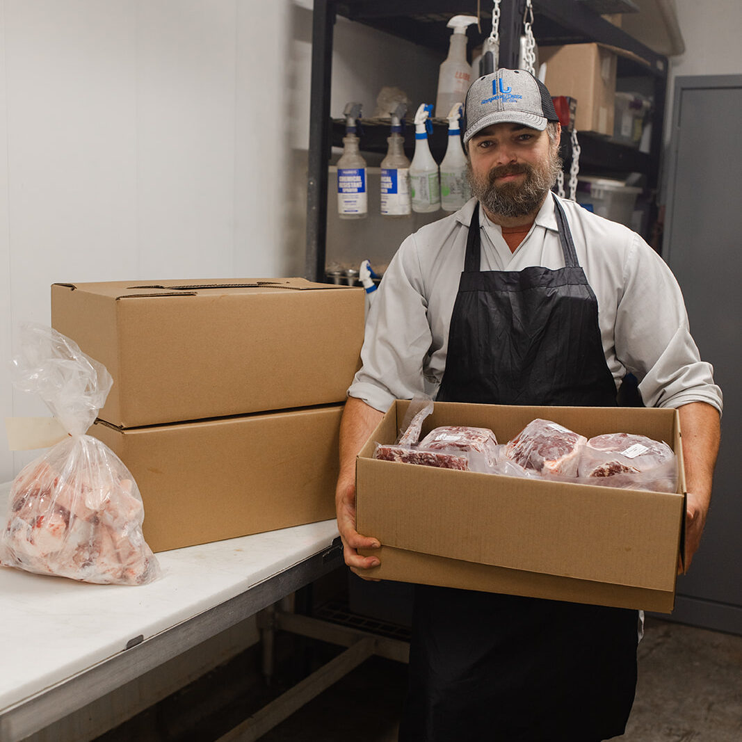 Rangeland Meats employee holding a box of freshly processed and packaged beef ready for customers